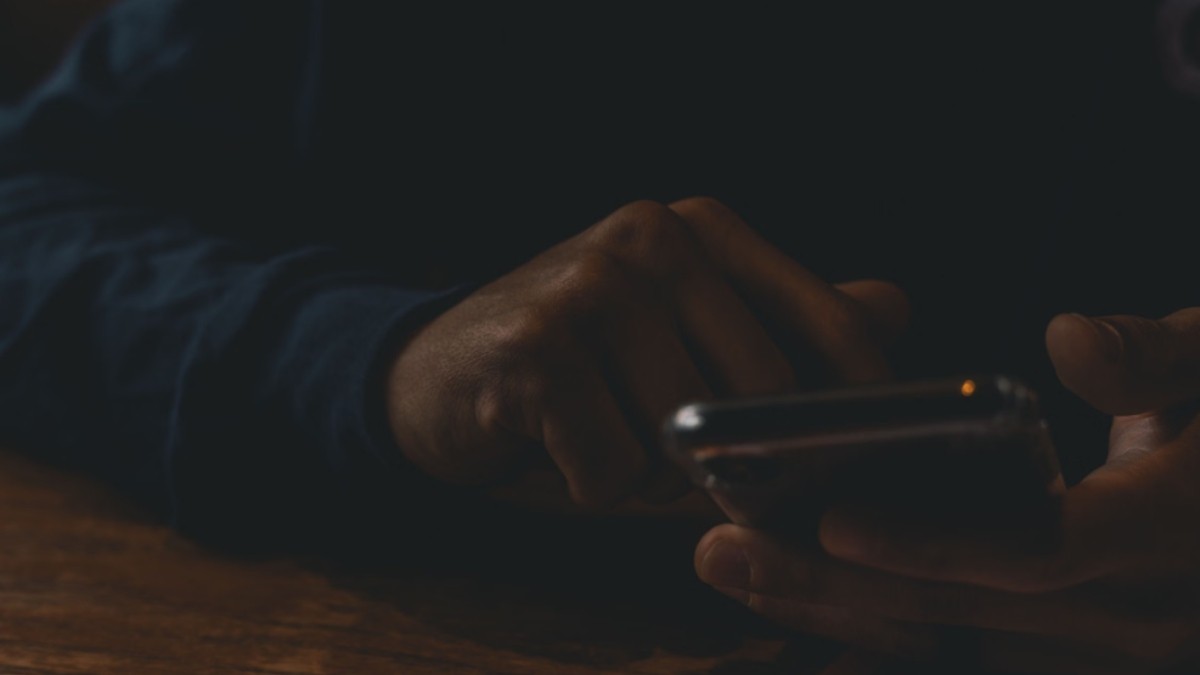Person doomscrolling on a phone late at night before bed.